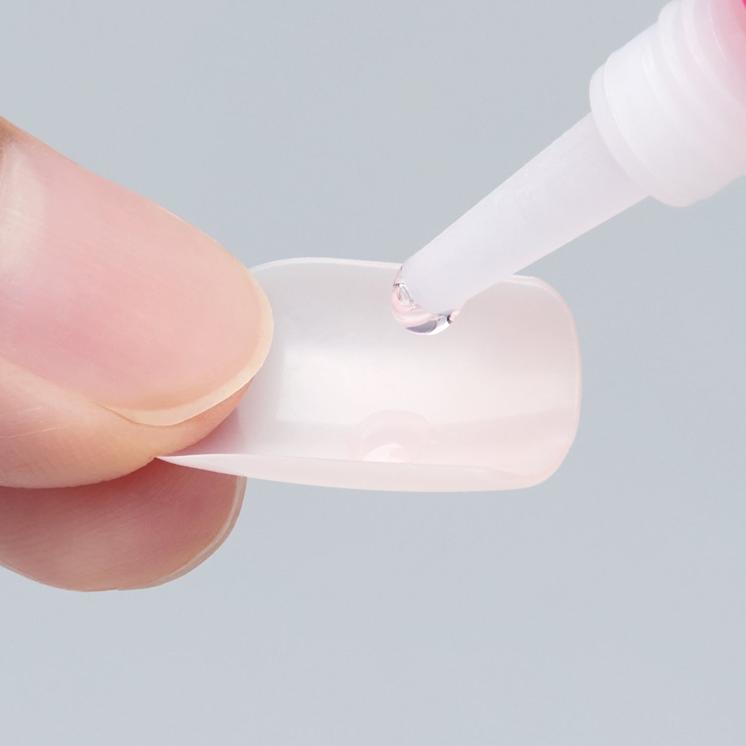 Close-up of nail glue being applied to an artificial nail by KISS. One of the steps to quick, easy nail application that lasts for days. 