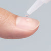 Close-up of nail glue being applied to a natural nail as part of the KISS artificial nail application that's quick and easy for lasting nails. 