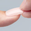 Close-up of a person applying an artificial nail from KISS on top of a natural nail as part of the quick and easy nail application process.